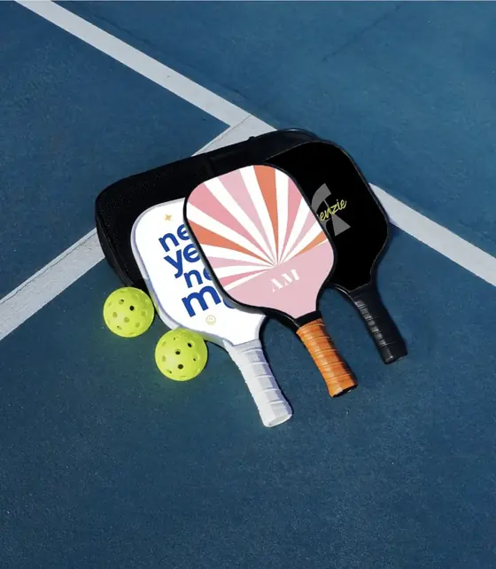 Two custom paddles with a matching cover and printed balls on a court